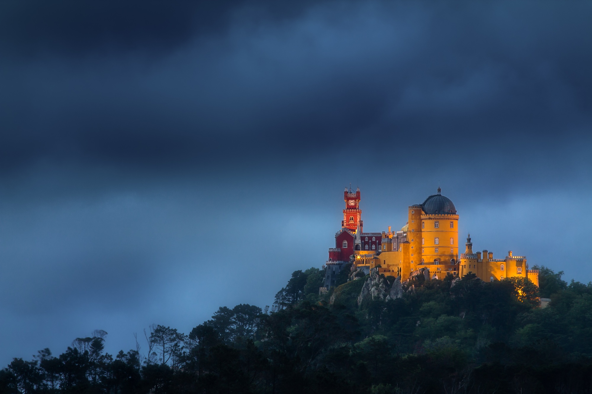 Historic Palacio da Pena building illuminated in a stormy sky in Sintra, Portugal